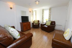 een woonkamer met lederen meubels en een flatscreen-tv bij Chapman's in Stornoway