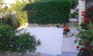ogród z białą podłogą i żywopłotem w obiekcie Apartments Magda w mieście Supetar