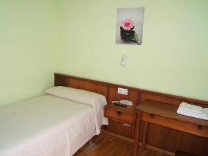 a room with two beds and a table and a picture at Hotel Severino in Ourense