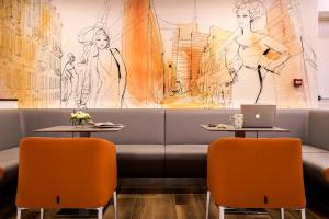 a restaurant with a couch and two tables with orange chairs at 43 Station Hotel in Milan