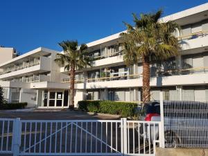 勒格羅－迪魯瓦的住宿－Plein cœur du Grau du Roi - Les Cigales de la Mer - 100m de la plage，停车场内棕榈树的公寓楼