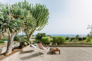 a couple of chairs and a table and trees at Villa del Quarzo in Siracusa