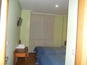 Habitación con 2 camas, mesa y ventana en Hotel Severino, en Ourense