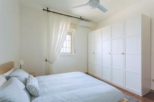 a white bedroom with a bed and a ceiling fan at Villa del Quarzo in Siracusa