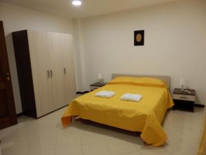 a bedroom with a yellow bed with two towels on it at B&B SoleLuna in Torretta