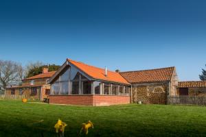 ein Backsteinhaus mit Fenstern auf einem grünen Rasen in der Unterkunft Little Abbey Farm in Gayton