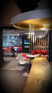 a living room with tables and chairs and a tv at Hôtel Baudouin in Valenciennes