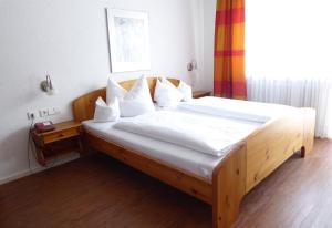 1 dormitorio con cama de madera con sábanas y almohadas blancas en Rommentaler Burgstüble, en Schlat