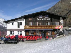 ein großes Gebäude mit roten Stühlen im Schnee in der Unterkunft Berghotel Furggstalden in Saas-Almagell