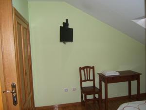 Habitación con mesa y TV en la pared. en Hotel Severino, en Ourense