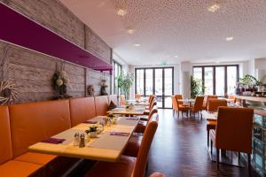 una sala da pranzo con tavoli e sedie in legno di Hotel Arooma a Erding