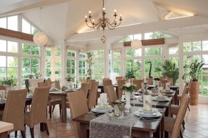 a dining room with tables and chairs and windows at Hotel Restaurant Zum Heidekrug in Bersenbrück