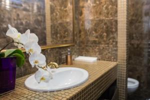 a bathroom sink with white flowers on a counter at Boutique Hotel Deluxe in Kamianets-Podilskyi