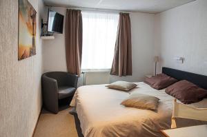 une chambre d'hôtel avec un lit, une chaise et une fenêtre dans l'établissement Hotel Halleux, à Banneux