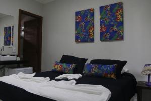a bed in a room with three paintings on the wall at Pousada Maria Bonita in Arraial d'Ajuda +15 photos