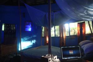 a bedroom with a bed with a laptop on a table at Green Zion Garden in Butre