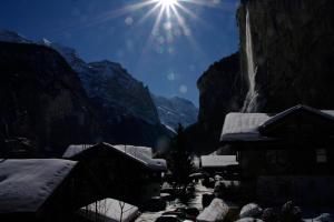 a snow covered village with a mountain in the background at Hotel Restaurant Jungfrau in Lauterbrunnen