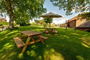two picnic tables and an umbrella in the grass at Dovestays in Laxton