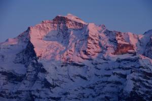 a mountain covered in snow with a blue sky at Hotel Restaurant Jungfrau in Lauterbrunnen