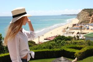 a woman wearing a hat looking at a beach at Clube Porto Mos - Sunplace Hotels & Beach Resort in Lagos