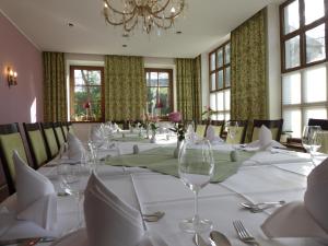 una sala da pranzo con tavolo, tovaglie bianche e bicchieri da vino di Hotel & Restaurant Kleinolbersdorf a Chemnitz