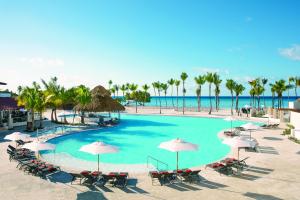 a large pool with chairs and umbrellas on the beach at Dreams Dominicus La Romana Resort & Spa in Bayahibe