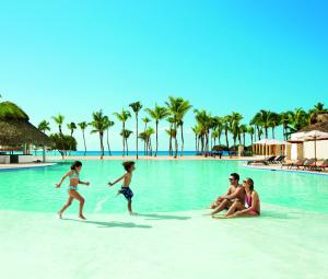 Dreams Dominicus La Romana Resort & Spa في باياهيب: مجموعة من الناس يلعبون في الماء على الشاطئ