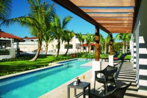 Dreams Dominicus La Romana Resort & Spa في باياهيب: مسبح وكراسي وطاولة بجانب منزل