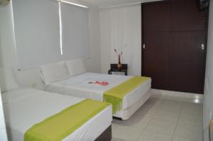 una habitación de hotel con 2 camas y una puerta en Hotel Casa Pablo en Neiva