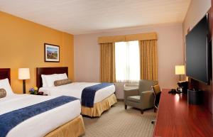 a hotel room with two beds and a flat screen tv at The Wylie Inn and Conference Center at Endicott College in Beverly