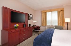 a hotel room with a bed and a flat screen tv at The Wylie Inn and Conference Center at Endicott College in Beverly