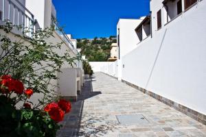 a pathway between two white buildings with red flowers at Poseidon Residence in San Vito lo Capo