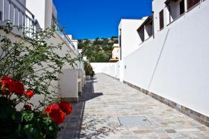 un percorso tra due edifici bianchi con fiori rossi di Poseidon Residence a San Vito lo Capo