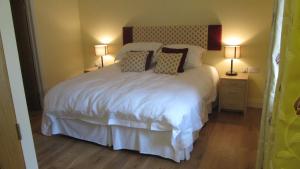 a bedroom with a large white bed with two lamps at Withyslade Farm in Tisbury