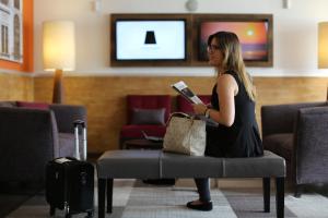 una mujer sentada en una silla sosteniendo un libro en Casa Andina Standard Miraflores San Antonio, en Lima