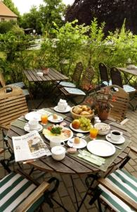 una mesa de madera con platos de comida. en Andersen Hotel Birkenwerder en Birkenwerder