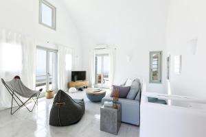 a white living room with a blue couch and chairs at Villa Vinea Santorini in Imerovigli