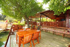 a wooden table and chairs on a deck with a tree at Dalyan Pension in Dalyan