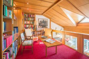 een bibliotheek met een tafel en stoelen en boekenplanken bij Hotel Haus Arenberg in Salzburg