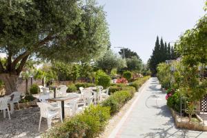 a patio with white chairs and tables in a garden at Eliofos Elegant Maisonettes in Polis Chrysochous