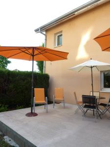 une terrasse avec une table, des chaises et des parasols dans l'établissement Lac'Hotel France, à Montréal La Cluse