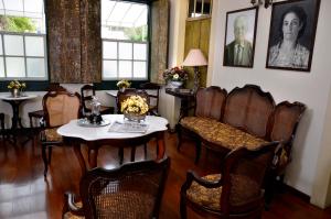 een eetkamer met een tafel, stoelen en ramen bij Casa do Manequinho Hotel e Restaurante in Piraí