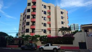 two cars parked in front of a tall building at Apartamento Atalaia Aracaju in Aracaju