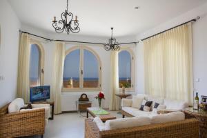 a living room with white furniture and large windows at Acropolis Sea View Villa in Polis Chrysochous