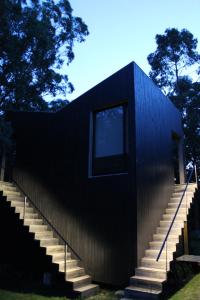 a black house with stairs leading up to it at Posada IRSIS in La Pedrera