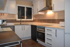 a kitchen with white cabinets and a sink at Sky Home Peñiscola in Peniscola +20 photos