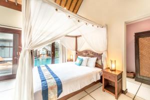 a bedroom with a canopy bed and a pool at Villa Frangipani in Sanur