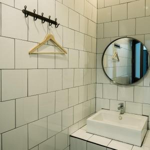 a white tiled bathroom with a sink and a mirror at Fashen Poshtel in Chiang Mai