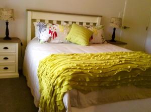 a bedroom with a bed with a yellow blanket on it at Bethlehem Garden Retreat in Tauranga
