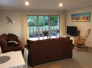 a living room with two couches and a large window at Bethlehem Garden Retreat in Tauranga